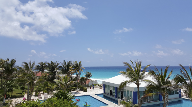 The restaurant at Solymar Beach Resort surrounded by a pool and palm trees.
