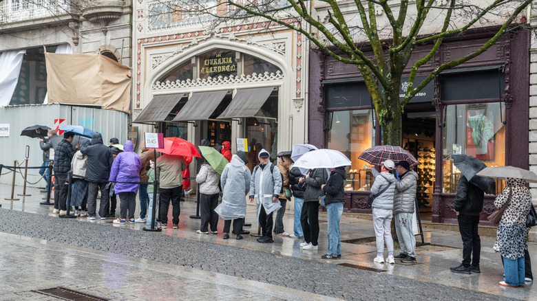 Queue of tourists with umbrellas in the rain