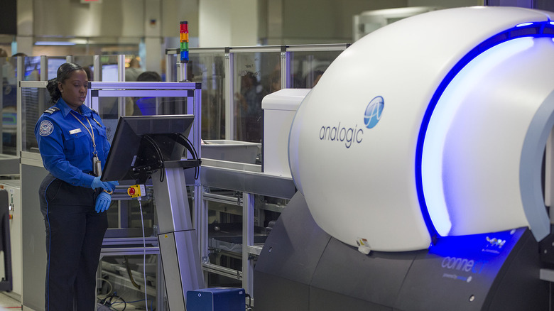 TSA agent standing beside CT scanner